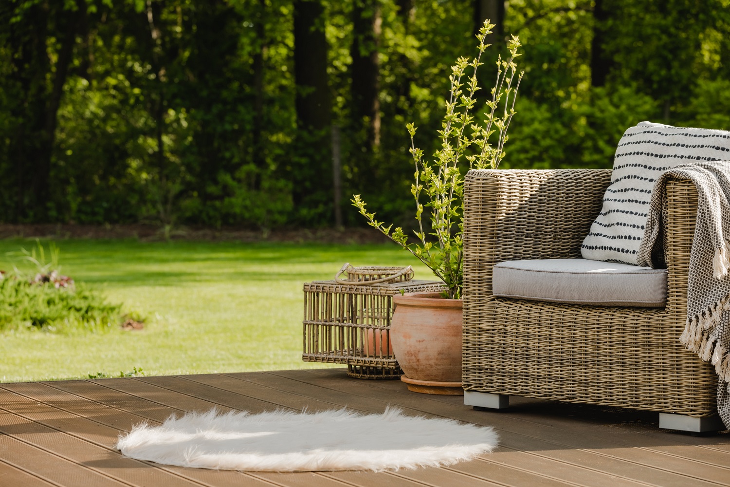 Fauteuil-en-osier-avec-oreiller-sur-terrasse-verte-dans-un-beau-jardin